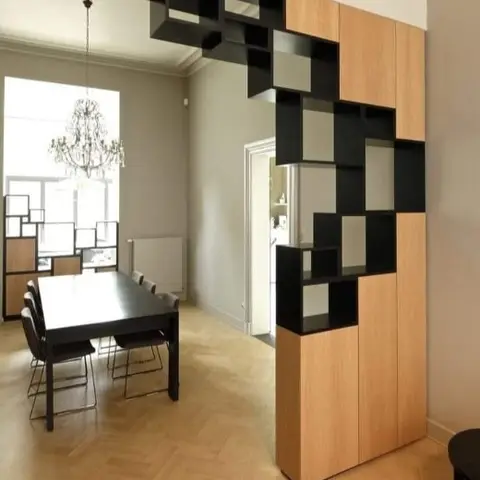 Dining room with a sculptural black-and-oak modular cube shelving unit dividing the space
