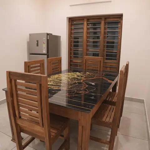 Dining room with a solid teak six-seater whose black glass top is hand-painted with a golden tree and a bird, slatted-back teak chairs around it
