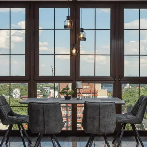 Dining room with a stone-top table and grey velvet upholstered chairs on angled metal legs, wire-cage pendant lights