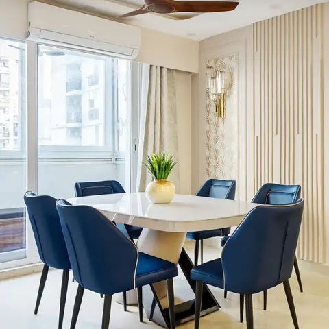 Dining room with a white marble-top table and navy-blue upholstered chairs, a fluted wood-panelled accent wall