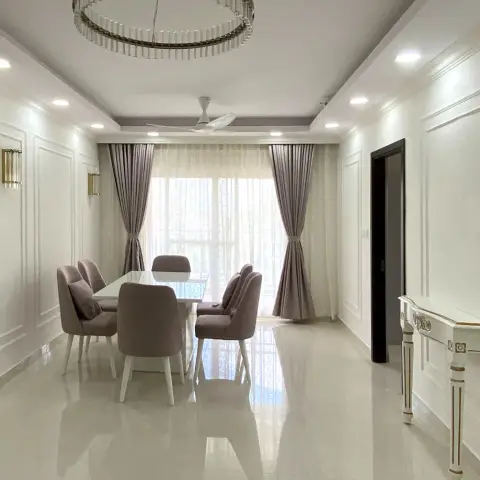 Dining room with a white six-seater table and dusty-mauve upholstered chairs under a crystal ring chandelier, panel mouldings picked out on cream walls