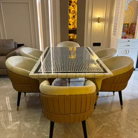 Dining set with a mother-of-pearl inlaid geometric-pattern table and mustard velvet channel-tufted barrel chairs, glossy marble floor