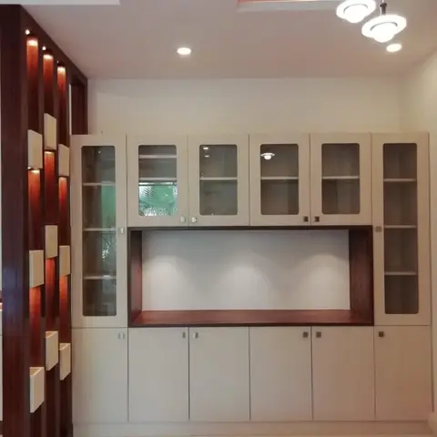 Dining space with a full-height glass-front crockery unit, backlit display niches on a wood partition, and cluster pendant lighting