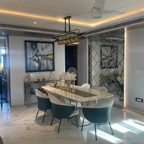 Dining space with a marble-top table, teal velvet armchairs, and a diamond-pattern mirrored wall reflecting the room.