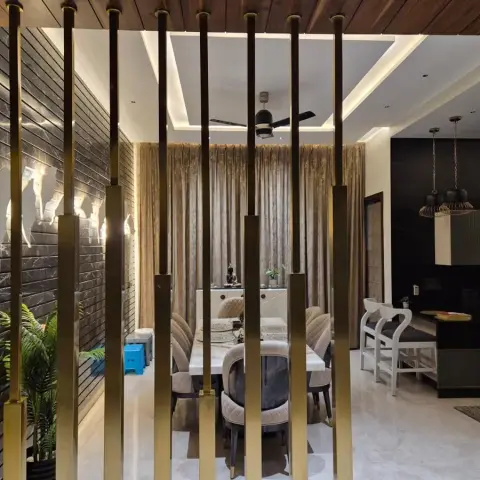 Dining table for six seen through a floor-to-ceiling brass vertical-rod screen, with a grooved dark-marble wall and wood-clad ceiling behind