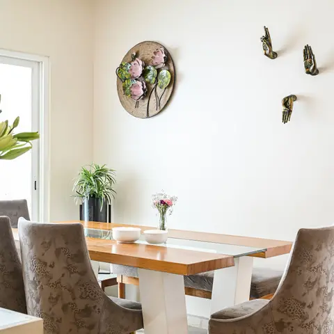 Dining table with a wood-and-glass top on a white pedestal base, surrounded by taupe animal-print upholstered chairs