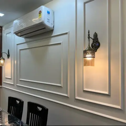Dining wall in cream with applied rectangular mouldings and two antique-brass sconces with fluted glass shades