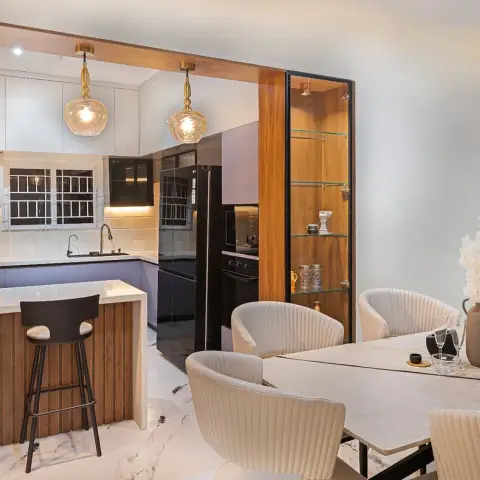 Dining zone with six channel-tufted cream chairs around a stone-top table beside a lit glass-and-teak display cabinet