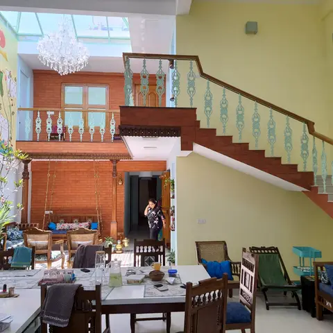 Double-height atrium dining and lounge space with a wrought-iron staircase, a brick-clad mezzanine with a traditional swing