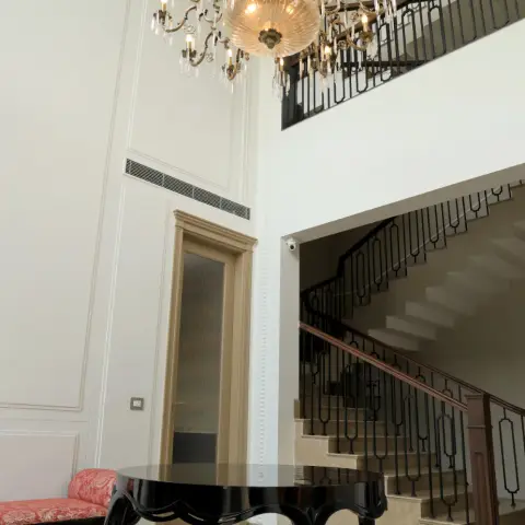 Double-height entrance hall with a brass and crystal chandelier over a black cabriole-leg centre table