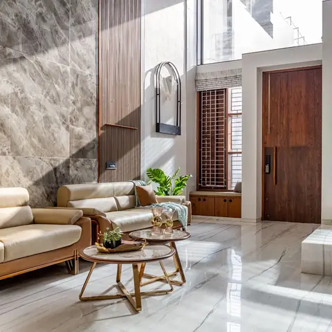 Double-height foyer-living space with a floor-to-ceiling grey marble feature wall, a fluted wood panel accent, a carved wooden main door