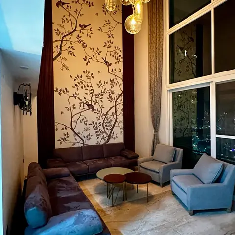 Double-height living nook with a hand-painted bird-and-branch mural wall, a cluster of amber glass pendant lights