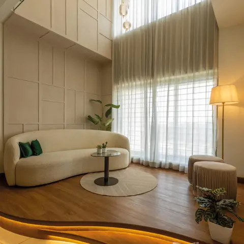 Double-height living room with a curved boucle sofa, floor-to-ceiling sheer curtains, a cluster of bubble pendant lights