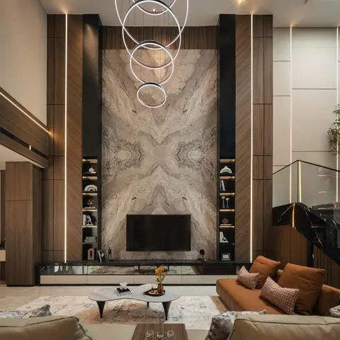 Double-height living room with a bookmatched marble TV wall flanked by backlit wood-panelled display niches, beneath a cascading multi-ring chandelier.