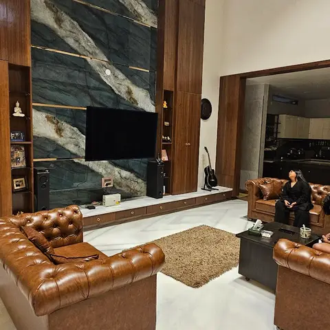 Double-height living room with a marble-and-brass inlay TV feature wall flanked by tall wood cabinetry