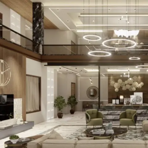 Double-height living room with a beige sectional sofa, olive-green armchairs, marble flooring, and a cluster of ring-shaped pendant lights beneath a mezzanine