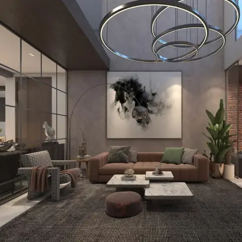 Double-height living room with a brown channel-tufted sofa and houndstooth armchair beneath a large abstract artwork and a layered circular ring chandelier.