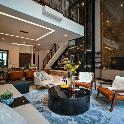 Double-height living room with a dark book-matched marble feature wall lit by gold accent strips, tan leather lounge chairs around a black round coffee table