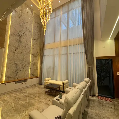 Double-height living room with a book-matched marble feature wall, a multi-tier crystal chandelier, floor-to-ceiling sheer curtains