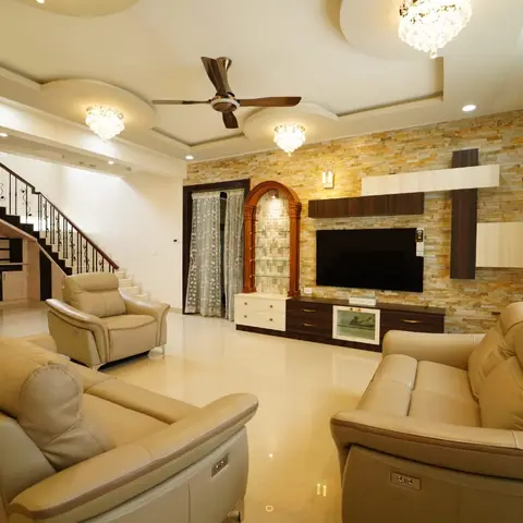 Double-height living room with a natural stone-clad TV wall, an arched glass display niche with accent lighting, beige leather reclining sofas