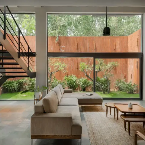 Double-height living room with an open-riser steel-and-timber stair, an exposed brick wall carrying the TV above a turquoise sideboard