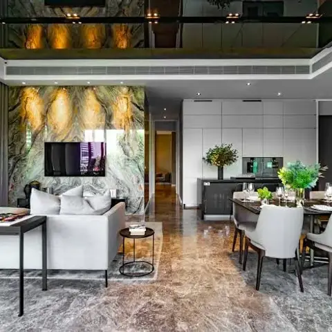 Double-height open plan where a book-matched green-and-amber quartzite slab wall carries the TV between living and a ten-seat dining table