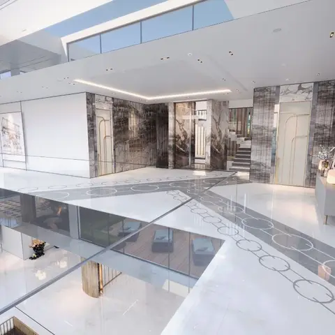 Double-height villa foyer with a circular-pattern inlaid marble floor, book-matched stone-clad walls with brass arch trim