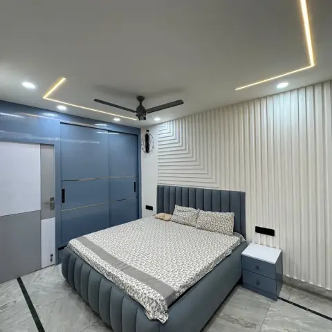 Dusty-blue bedroom with a channel-tufted upholstered bed and a matching sliding wardrobe with brass inlay lines