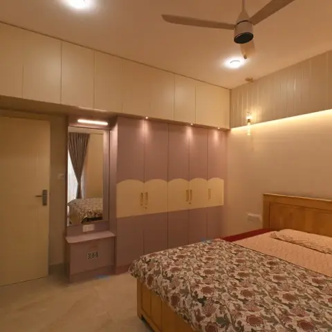 Dusty-mauve and cream wardrobe run with a scalloped two-tone shutter break and full-height lofts