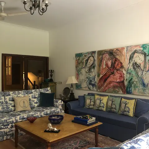 Eclectic Indian living room with blue-and-white patterned sofas, an antique Persian-style rug and a three-panel figurative painting