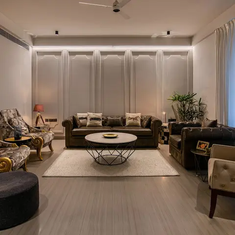 Eclectic living room with dark leather chesterfield sofas facing floral wingback armchairs and a tall tufted wingback chair around a geometric wire-frame