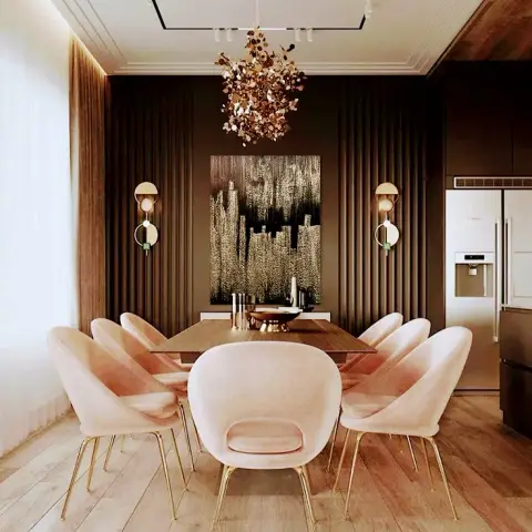 Eight blush velvet shell chairs on brass legs ringing a walnut table, under a gold-confetti chandelier