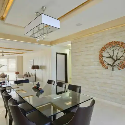 Eight-seater glass dining table with dark leather high-backs under a rectangular box pendant