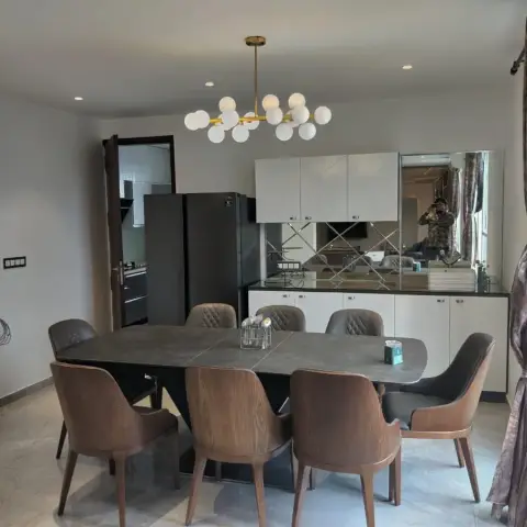 Eight-seater grey sintered-stone dining table under a brass sputnik globe chandelier