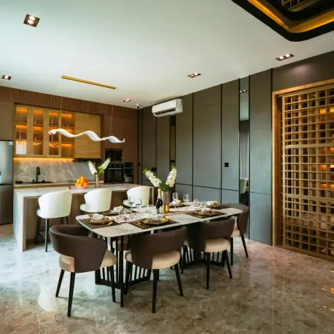 Eight-seater marble dining table laid under a ribbon-shaped LED pendant, with a lit oak crockery run and island kitchen behind it and a brass-framed square