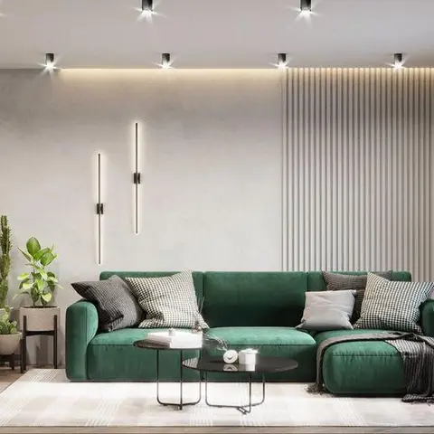 Emerald green sectional sofa with black-and-white patterned cushions facing black nesting coffee tables