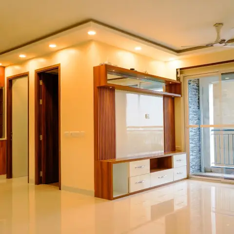 Empty apartment hall with a teak-framed TV unit with fluted side battens, white drawer fronts and a glass display shelf on the projecting wall