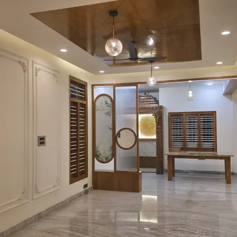 Empty entrance hall with ornate white wall-moulding panels, a wood-panelled ceiling with pendant lights, a fluted-glass partition screen