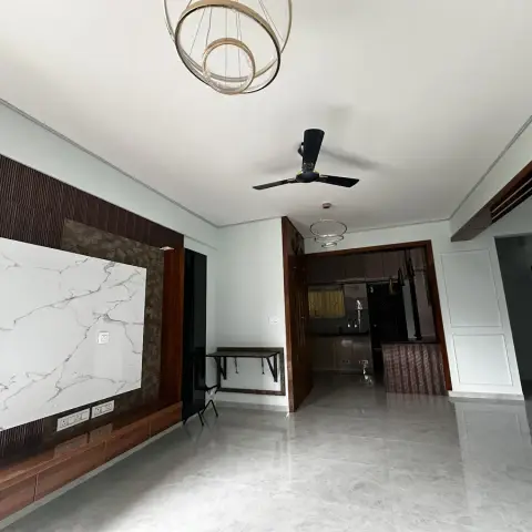 Empty handed-over living room where a dark fluted TV wall carries a white marble slab panel over a low walnut console