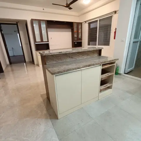 Empty living-dining area with a granite-top bar counter with wicker-basket shelving and a walnut-veneer TV/crockery unit
