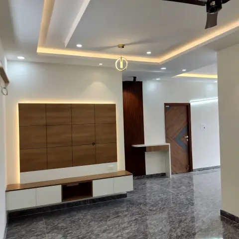 Empty living room with a backlit teak panel routed into a four-by-three grid above a white-and-wood floating console, a small brass ring pendant