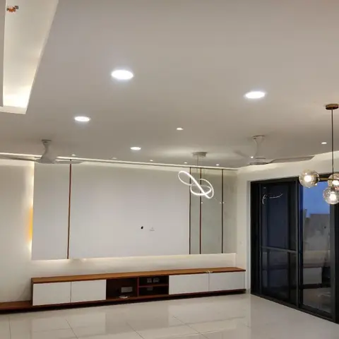 Empty living room with a floating wood-and-white TV console against a marble accent wall, twin ceiling fans
