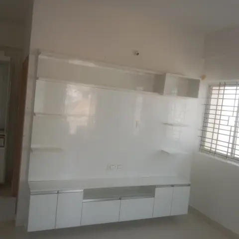 Empty living room with a floating high-gloss white TV unit featuring asymmetric open shelving, grille windows