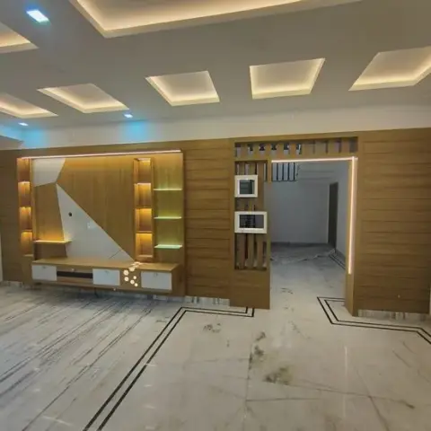 Empty living room with a teak-laminate TV wall, angular backlit niches and a slatted partition framing the passage to the next room