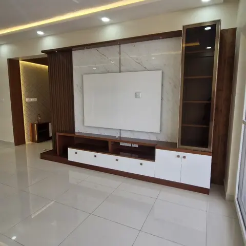 Empty living room with a walnut-framed TV wall featuring a bookmatched marble backdrop panel, a glass display cabinet, and a white-and-wood console below
