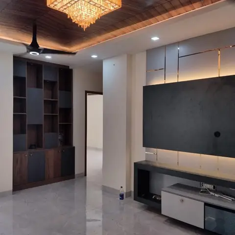Empty living room with a wood-slat cove ceiling, a crystal chandelier, dark stone-effect TV wall with brass inlay lines
