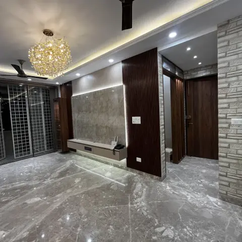 Empty living room with dramatic grey-veined marble flooring, a crystal cluster chandelier, a marble and fluted wood TV wall
