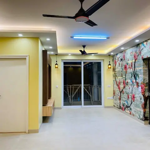 Empty living room with sunflower-yellow walls, a cove-lit false ceiling with two ceiling fans