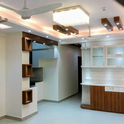 Empty open-plan living-dining-kitchen area with a stepped POP ceiling, crystal box pendant light, wood display niche column