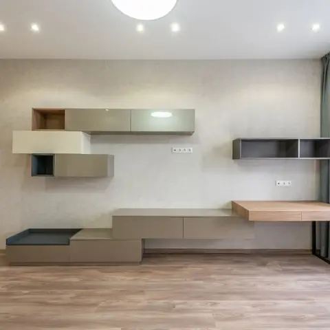 Empty room with an asymmetric floating storage wall of staggered taupe and white gloss boxes at varying heights